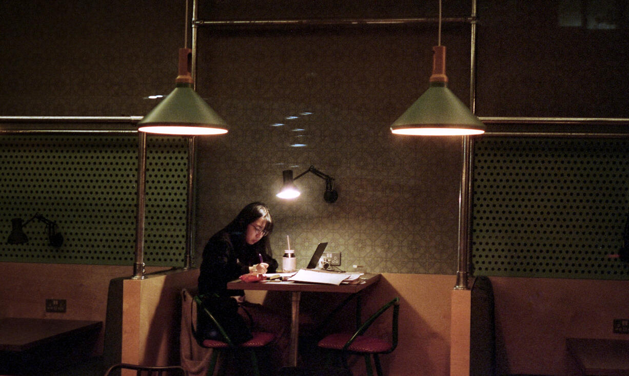 Lone diner working at a table in a dimly lit restaurant Lone diner working at a table in a dimly lit restaurant