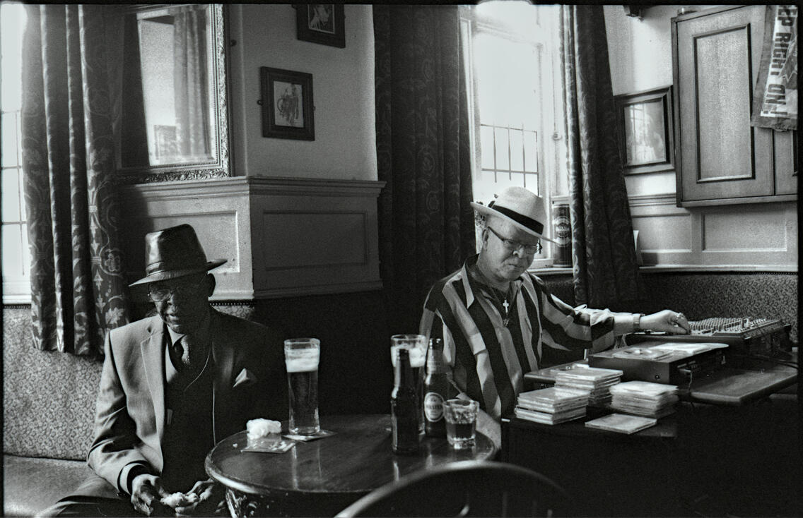 Two men in hats sharing a drink in a pub Two men in hats sharing a drink in a pub