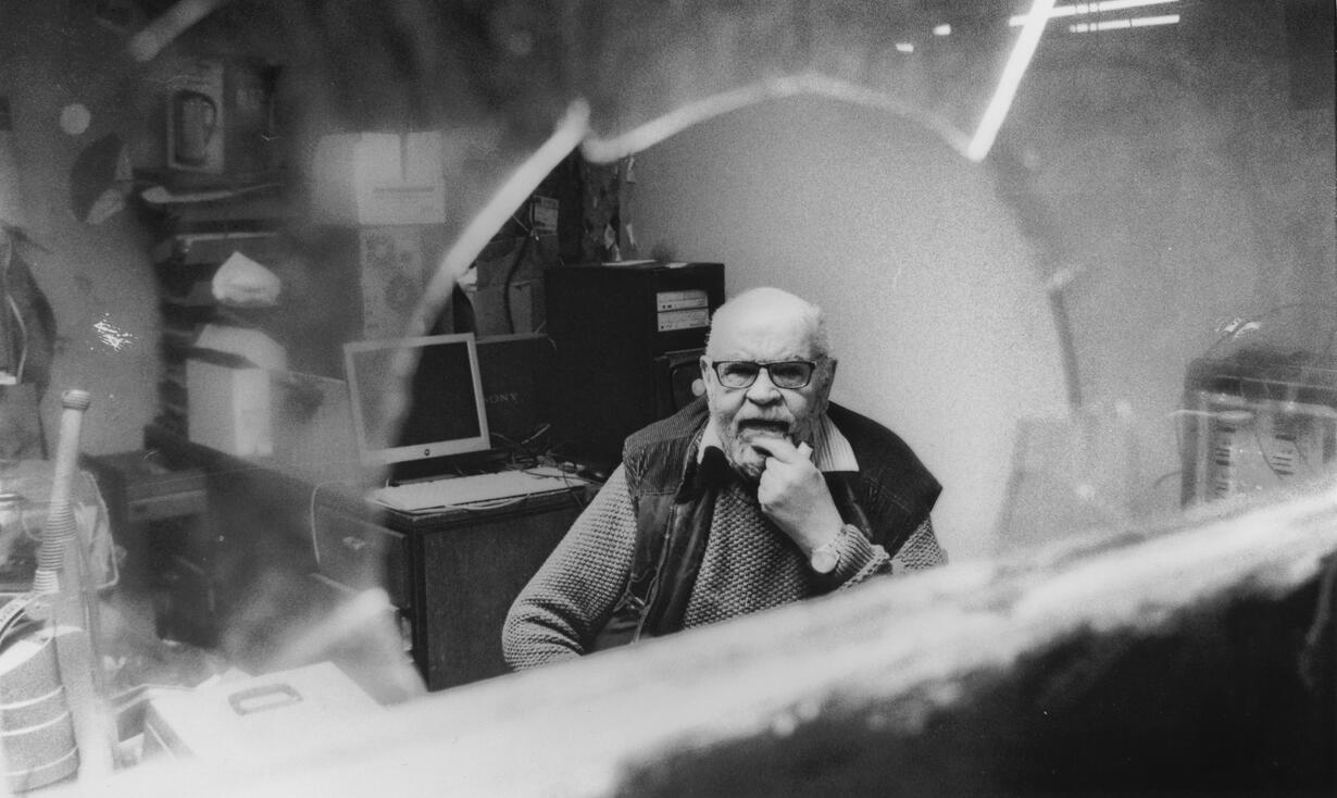 Shopkeeper behind the window of his cluttered repair shop Shopkeeper behind the window of his cluttered repair shop