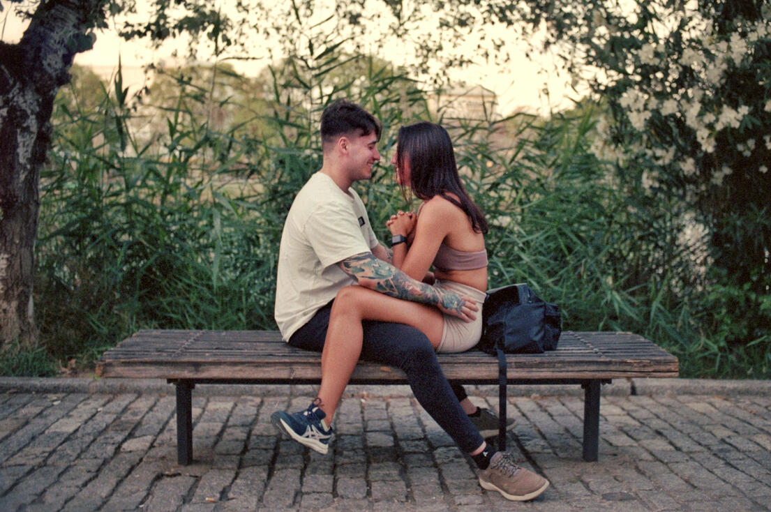 Couple embracing on a riverside bench at dusk, Seville Couple embracing on a riverside bench at dusk, Seville