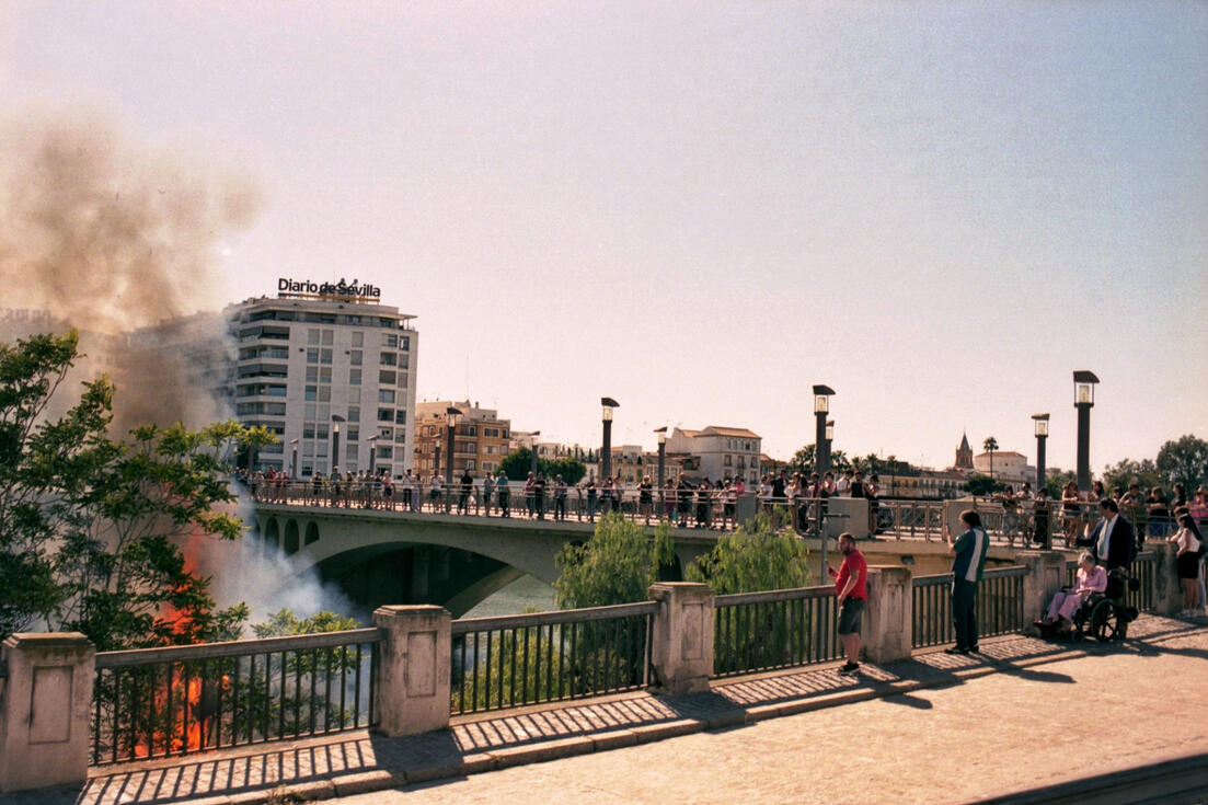 Crowd on a Seville bridge watching smoke rise over the river Crowd on a Seville bridge watching smoke rise over the river
