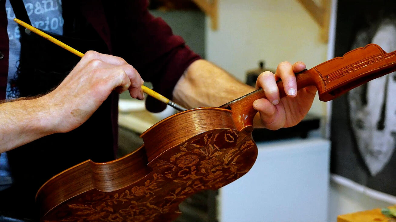 Luthier's hands varnishing the scroll of a violin Luthier's hands varnishing the scroll of a violin