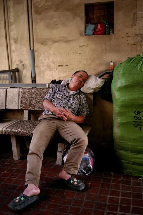 Man asleep on a stone bench in a Hanoi market Man asleep on a stone bench in a Hanoi market